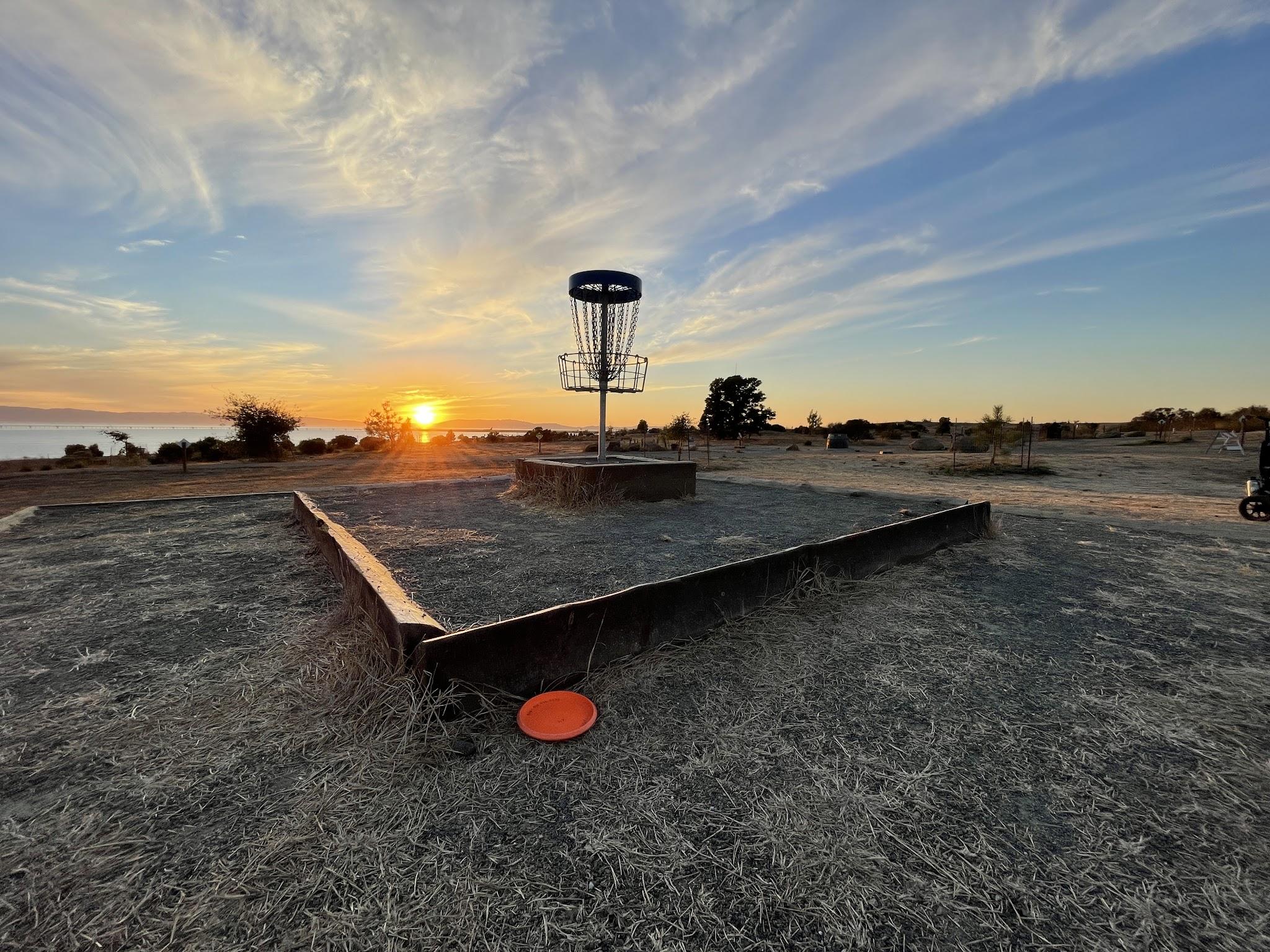 Sunset over the Oyster Bay disc golf course and an elevated basket